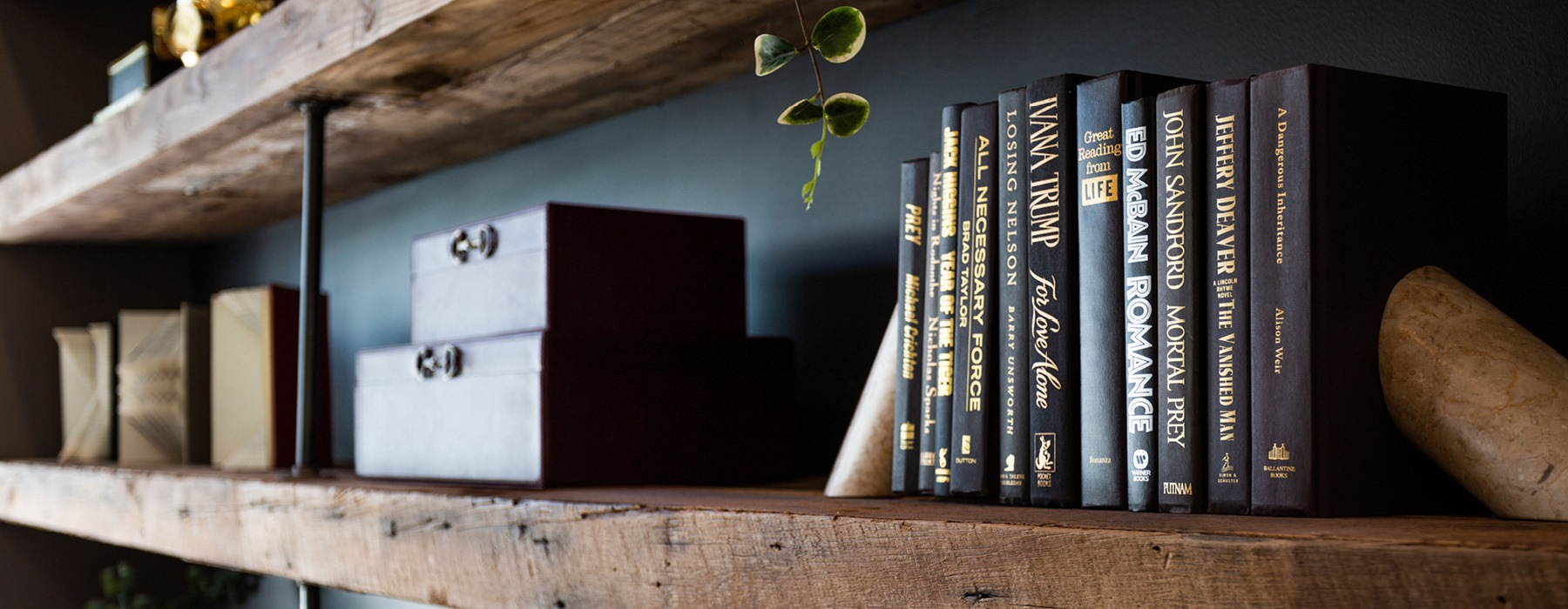 staged wood bookshelves against dark, bluish grey wall